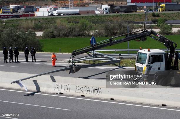 Sign reading 'Spanish bitch' is seen as a crane lifts remains of a road blockade set up by Catalan separatists on AP-7 motorway linking Spain to...