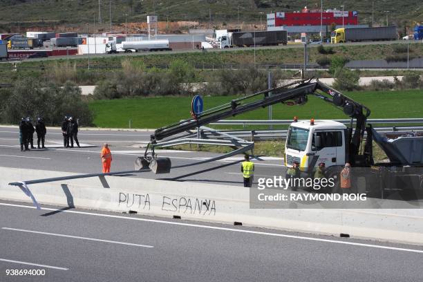 Sign reading 'Spanish bitch' is seen as a crane lifts remains of a road blockade set up by Catalan separatists on AP-7 motorway linking Spain to...