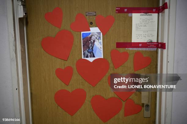 Picture taken on March 27, 2018 shows a picture of Mireille Knoll, heart-shaped documents and seals of the police posted on the door of her apartment...