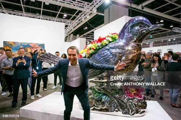 Artist Jeff Koons poses in front of his artwork 'Bluebird Planter' during the media preview of Art Basel in Hong Kong on March 27, 2018. / AFP PHOTO...