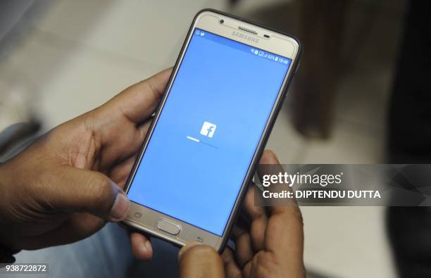 An Indian man poses for a photograph using Facebook on his cellpohne in Siliguri on March 27, 2018. - India's ruling and main opposition parties on...