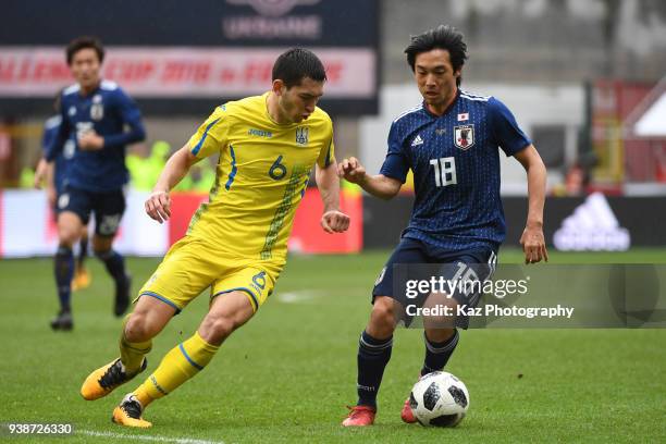 Shoya Nakajima of Japan keeps the ball the ball under the pressure from Taras Stepanenko of Ukraine at Stade Maurice Dufrasne on March 27, 2018 in...