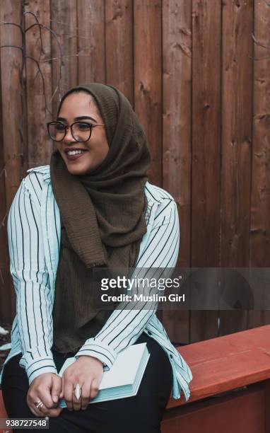 a muslim woman in olive-colored hijab, holding a book - muslimgirlcollection ストックフォトと画像