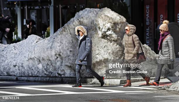 Pedestrians pass a snowbank on Boylston Street in Boston on March 26, 2018.