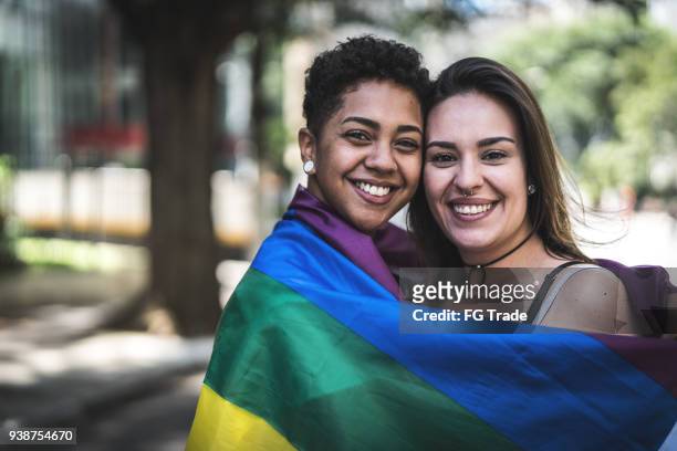 pareja de lesbianas con la bandera del arco iris - lesbian love fotografías e imágenes de stock
