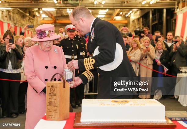 Queen Elizabeth II is presented with a bottle of HMS Ocean gin by commanding officer Captain Robert Pedre during a reception onboard the ship after...