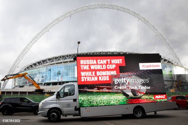 Billboard truck with the words "Russia Can't Host the World Cup While Bombing Syrian Kids" and an image of a bloodied football drives past Wembley...