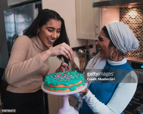 two muslim women putting sprinkles onto a cake - muslimgirlcollection ストックフォトと画像