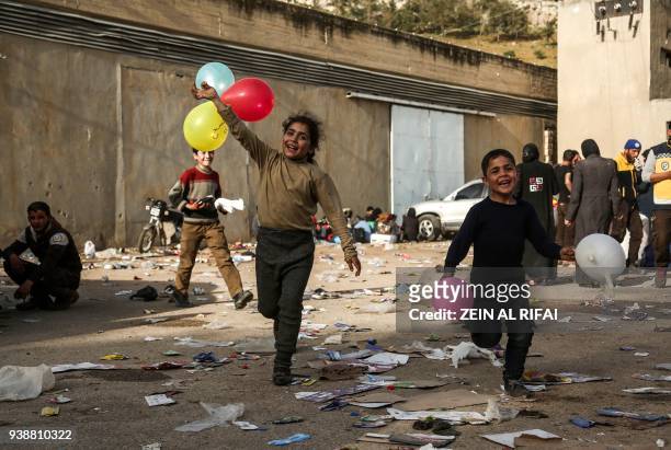 Syrian children evacuated from Eastern Ghouta run with balloons after arriving in the village of Qalaat al-Madiq, some 45 kilometres northwest of the...