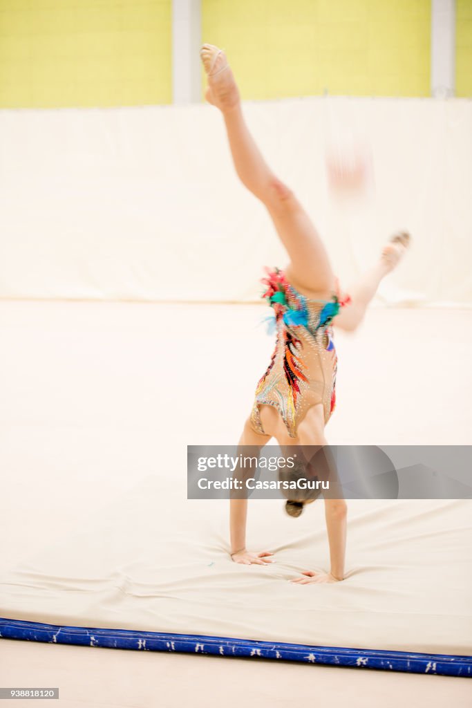 Young Rhythmic Gymnastics Athlete Catching the Ball with Legs in Handstand