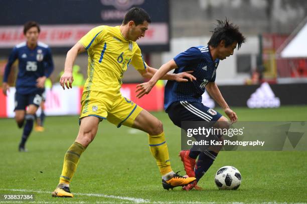 Shoya Nakajima of Japan keeps the ball under the pressure from Taras Stepanenko of Ukraine during the international friendly match between Japan and...