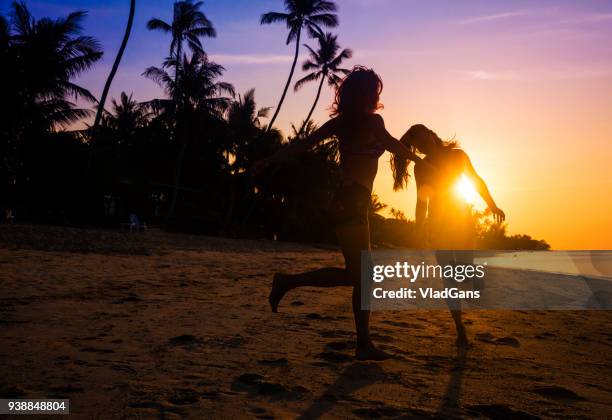 freunde, tanzen auf einem sonnenuntergang strand - junge frau strand sand springen stock-fotos und bilder