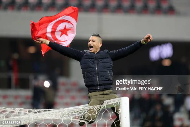 Tunisian supporter holding a flag of Tunisia, sits on a goal post, celebrates after his team won 1-0 at the end of of the international friendly...