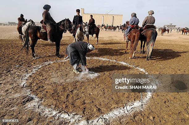 An Afghan man highlights with lime a circle on the Buzkashi grounds during Afghanistan's traditional game of Buzkashi in the northern town of...