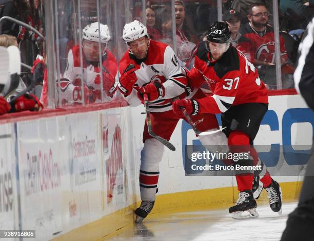 Justin Williams of the Carolina Hurricanes and Pavel Zacha of the New Jersey Devils battle for the puck along the boards during the first period at...