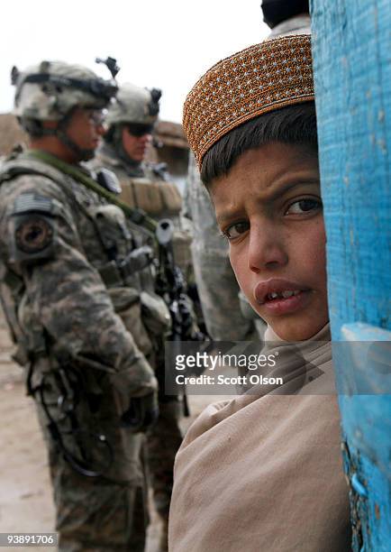 Child watches as soldiers from the Army's Blackfoot Company 1st Battalion 501st Parachute Infantry Regiment patrol through the business district on...