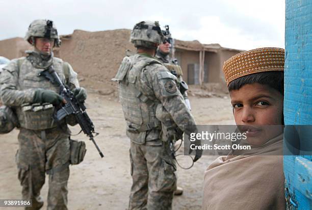 Child watches as soldiers from the Army's Blackfoot Company 1st Battalion 501st Parachute Infantry Regiment patrol through the business district on...