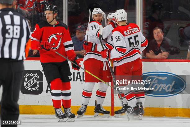 Phillip Di Giuseppe of the Carolina Hurricanes celebrates his first period goal with teammates as John Moore of the New Jersey Devils looks away...