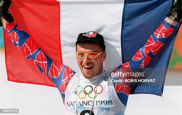 Jean-Luc Cretier of France holds the French flag after winning the men's Olympic downhill 13 February in Hakuba. Cretier won the race with a time of...