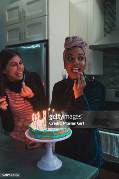 muslim women licking the candles on a lit birthday cake - muslimgirlcollection ストックフォトと画像