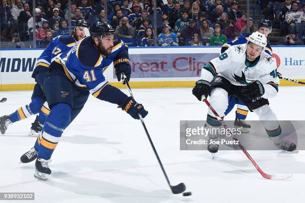 Robert Bortuzzo of the St. Louis Blues handles the puck as Tomas Hertl of the San Jose Sharks pressures at Scottrade Center on March 27, 2018 in St....