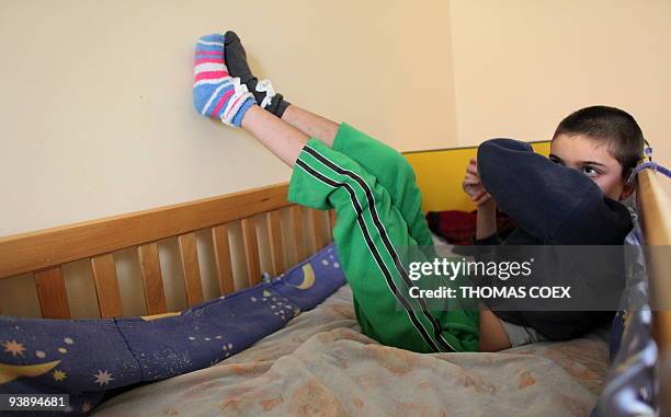 Disabled and orphaned Romanian child rests on his bed on November 24 at the Targu Jiu orphanage, southwestern Romania, after being transfered from...