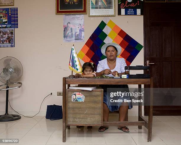 Tania Quiroz Patino the Secretary General of the farmer's federation of Chimore, Bolivia, chewing coca in her office in front of the indigenous flag....