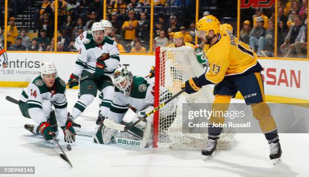 Nick Bonino of the Nashville Predators centers the puck against Joel Eriksson Ek and Devan Dubnyk of the Minnesota Wild during an NHL game at...