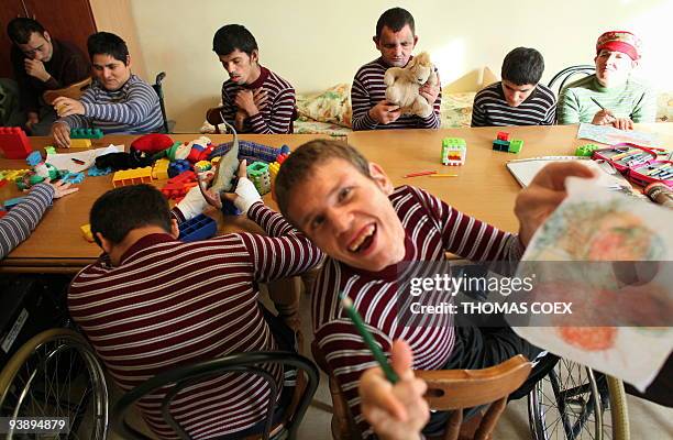 Disabled and orphaned Romanian adults play in a room on November 25 at the Targu Jiu orphanage, southwestern Romania, after being transfered from...