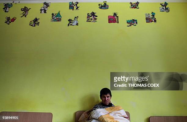 Disabled and orphaned Romanian adult hangs around in a room on November 25 at the Targu Jiu orphanage, southwestern Romania, after being transfered...