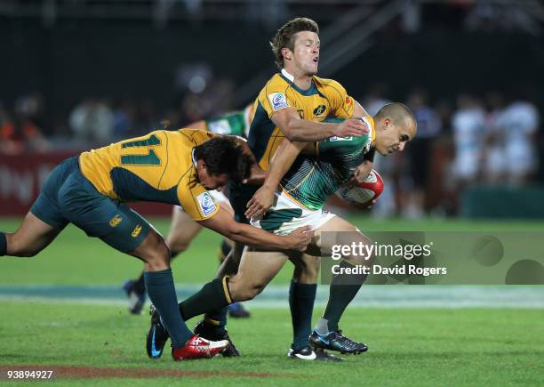 Paul Delport of South Africa is tackled by Joshua Sherrin and Tom Otton of Australia during the IRB Sevens tournament at the Dubai Sevens Stadium on...