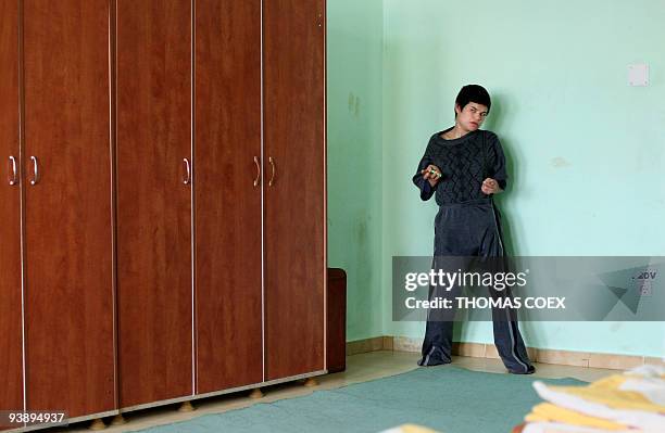 Disabled and orphaned Romanian adult waits alone in a room at the Targu Jiu orphanage on November 25 southwestern Romania, after being transfered...