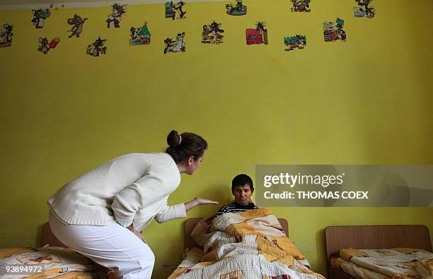 Woman talks with a disabled and orphaned Romanian adult on November 25 at the Targu Jiu orphanage, southwestern Romania, after being transfered from...