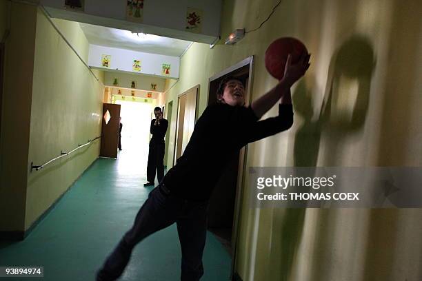 Disabled and orphaned Romanian adult plays with a ball in a corridor on November 26 at the Babeni orphanage, southwestern Romania. Twenty years after...