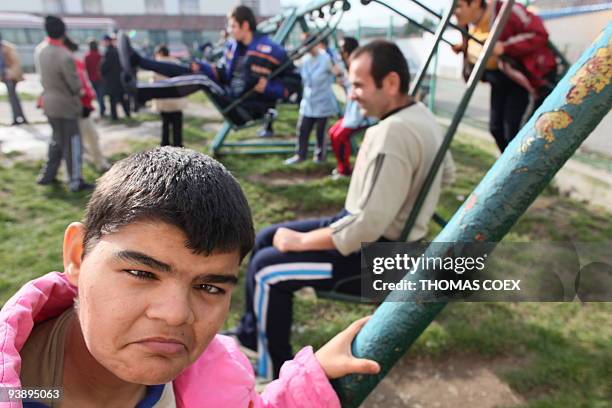 Disabled and orphaned Romanian adults have a go on a swing at the Targu Jiu orphanage on November 25 southwestern Romania, after being transfered...