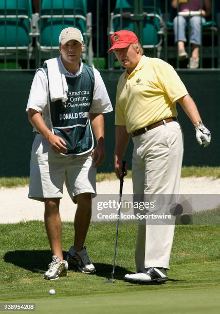 Businessman Donald Trump talks with a caddie before putting the ball during the 2006 American Century Celebrity Golf Tournament played at the...