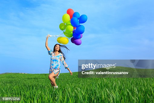 Fröhliche junge Frau bunte Ballons halten und laufen Fröhliche junge Frau bunte Ballons halten und laufen