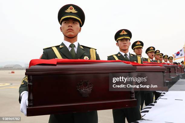 Chinese soldiers carry caskets containing the remains of Chinese soldiers during the handing over ceremony at the Incheon International Airport on...