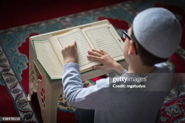 rapaz muçulmano ler o alcorão sagrado em mesquita - holy quran - fotografias e filmes do acervo