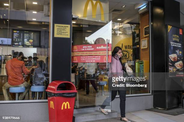 Customer uses a smartphone while exiting a McDonald's Corp. Restaurant, operated by Hardcastle Restaurants Pvt., in Mumbai, India, on Tuesday, March...