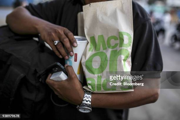 Customer carries take-out food from a McDonald's Corp. Restaurant, operated by Hardcastle Restaurants Pvt., in Mumbai, India, on Tuesday, March 20,...