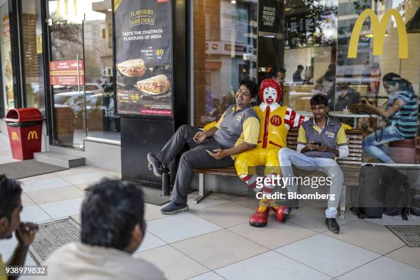 Food delivery couriers sit next to a statue of Ronald McDonald outside a McDonald's Corp. Restaurant, operated by Hardcastle Restaurants Pvt., in...