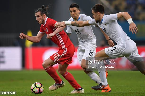 Gareth Bale, left, of Wales national football team kicks the ball to make a pass against players of Uruguay national football team in their final...