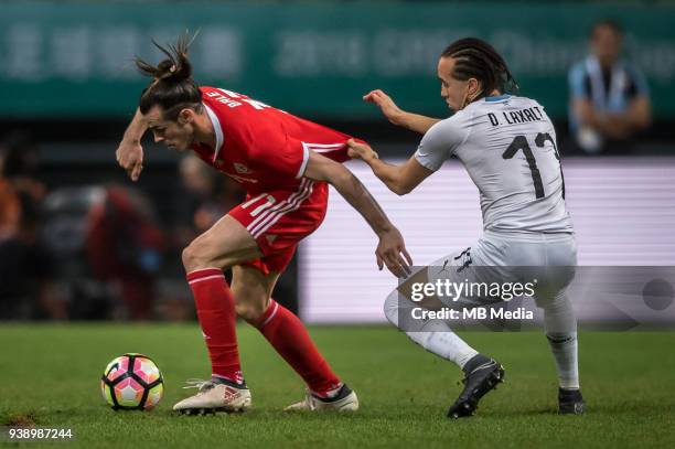 Gareth Bale, left, of Wales national football team kicks the ball to make a pass against Diego Laxalt of Uruguay national football team in their...