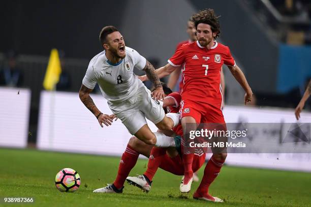 Joe Allen, right, of Wales national football team kicks the ball to make a pass against Nahitan Nandez of Uruguay national football team in their...