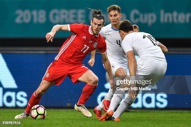 Gareth Bale, left, of Wales national football team kicks the ball to make a pass against players of Uruguay national football team in their final...