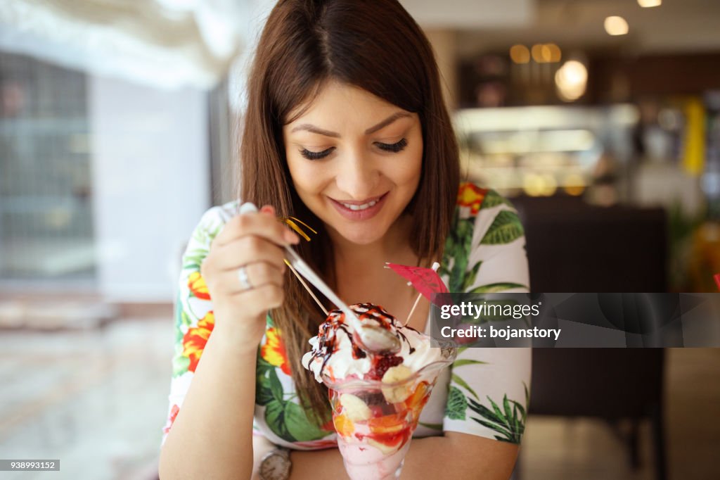 Jonge zwangere vrouw sundae eten in café