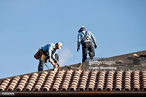 Roofers fix tile to the roof of the new Institute For Economic Policy Research building at Stanford University in Palo Alto, California, U.S., on...