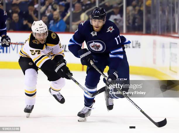 Adam Lowry of the Winnipeg Jets plays the puck down the ice as Tommy Wingels of the Boston Bruins gives chase during second period action at the Bell...