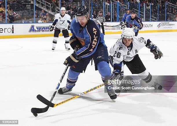 Todd White of the Atlanta Thrashers battles for the puck against Martin St. Louis of the Tampa Bay Lightning at Philips Arena on November 22, 2009 in...